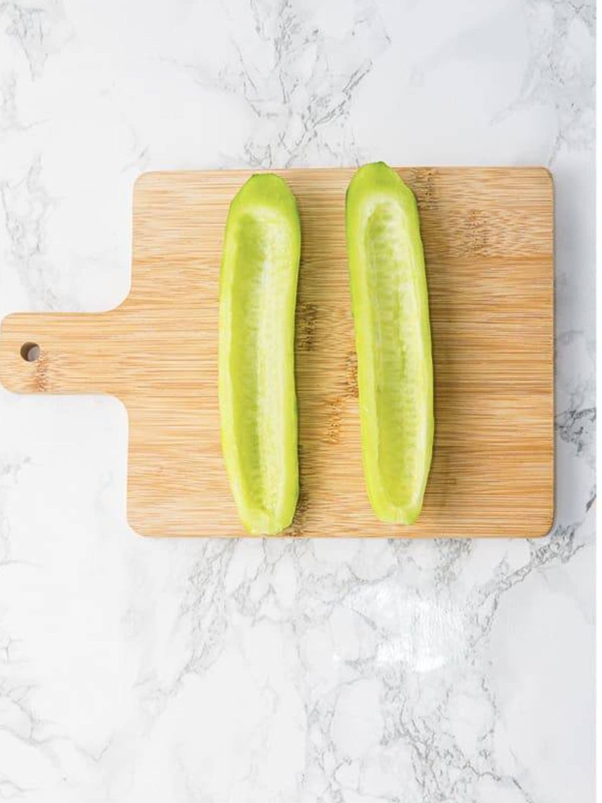 Grating fresh cucumber on a wooden board to make tzatziki sauce.