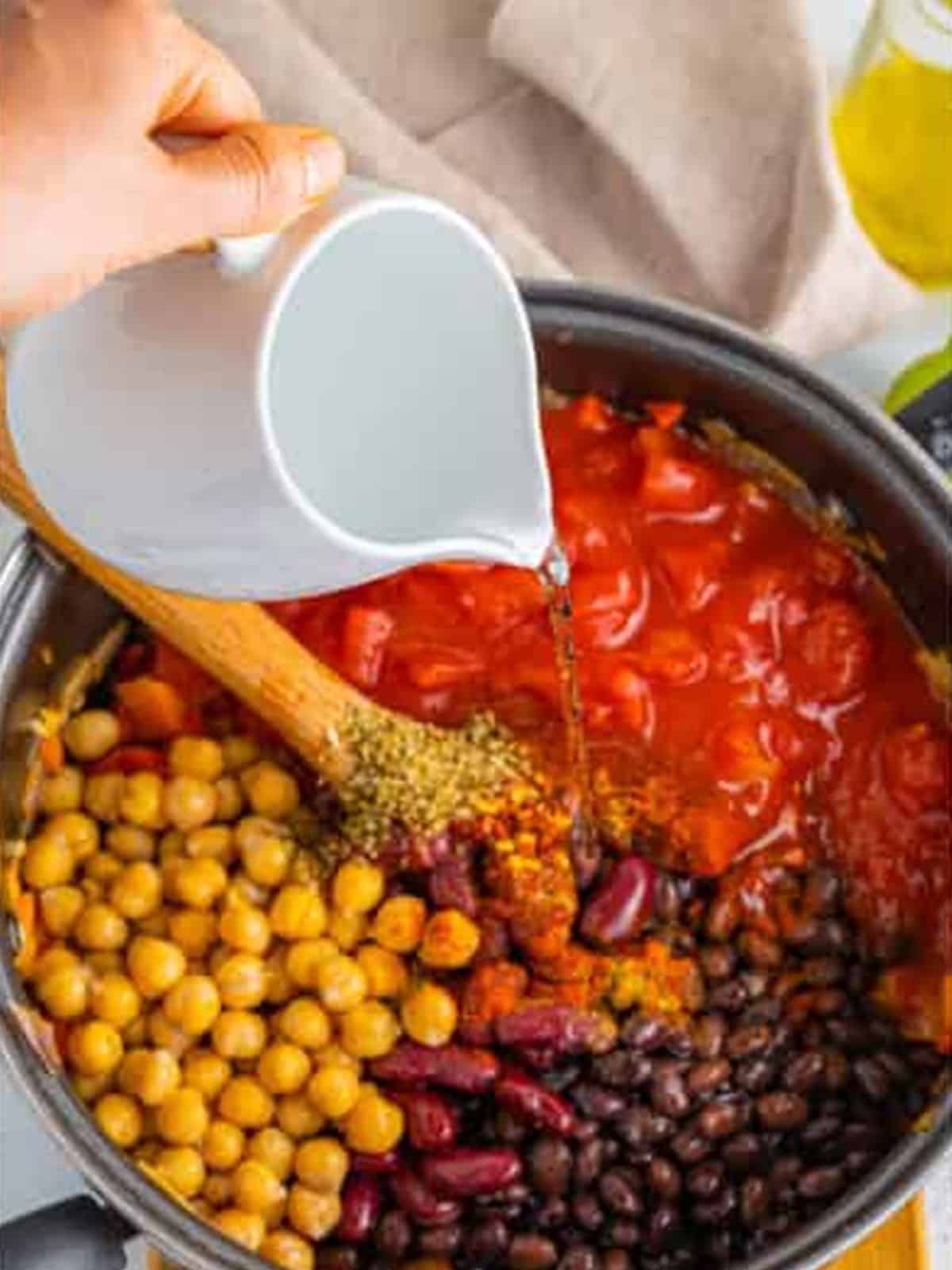 Beans, chickpeas, crushed tomato, and spices added to the chili pot.