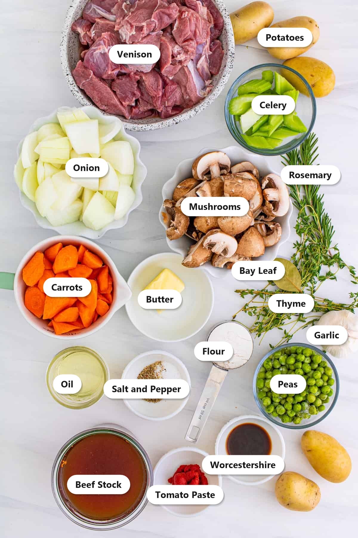 Labeled ingredients to make venison stew including venison, potatoes, carrots, onion, celery, mushrooms, peas, garlic, herbs, butter, flour, tomato paste, Worcestershire, and beef stock.