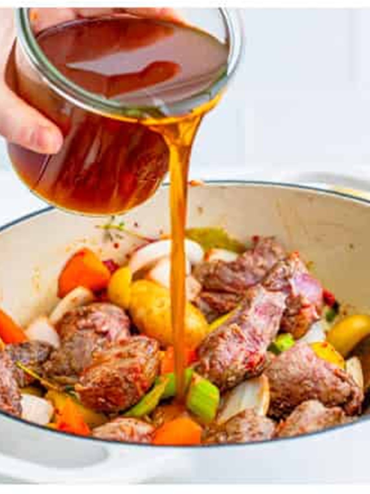 Beef stock poured into the Dutch oven of venison and vegetables.