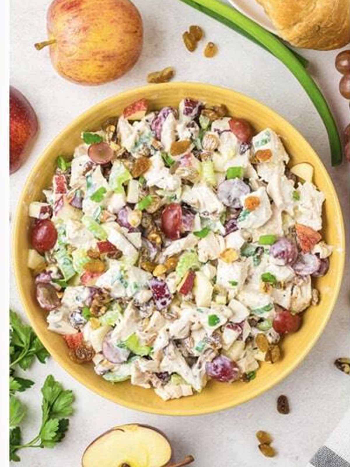 Finished waldorf chicken salad tossed together in a yellow bowl.