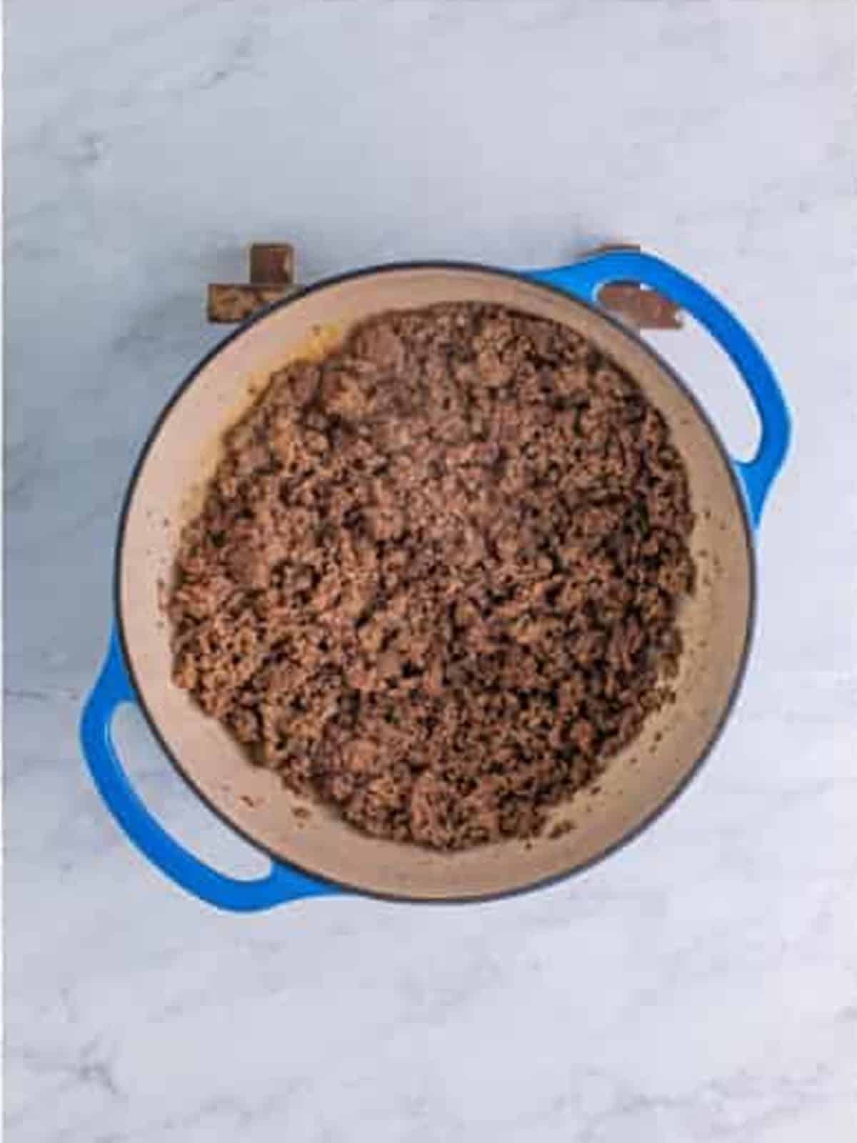 Ground beef browned and crumbled in a blue dutch oven for Wendys chili.