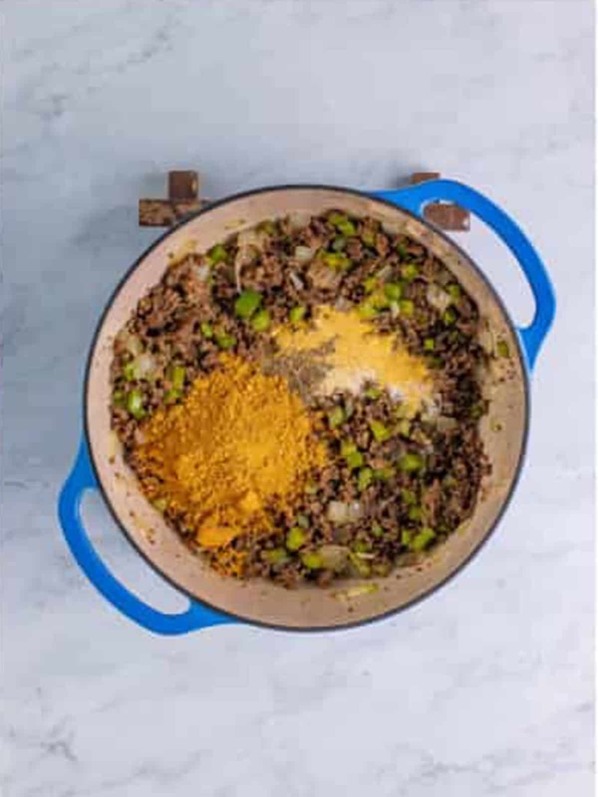 Chili seasoning and spices added to the beef and vegetables in the pot.