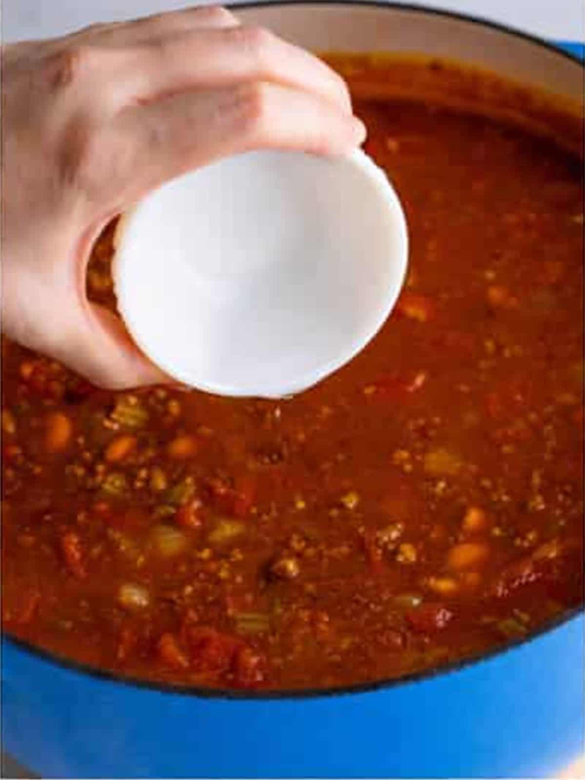 White vinegar being stirred into the finished simmered Wendys chili.