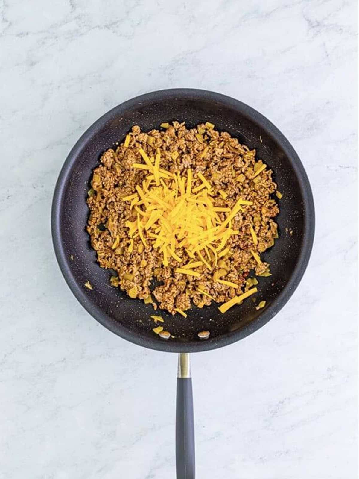 Shredded cheddar cheese stirred into the seasoned ground beef filling.