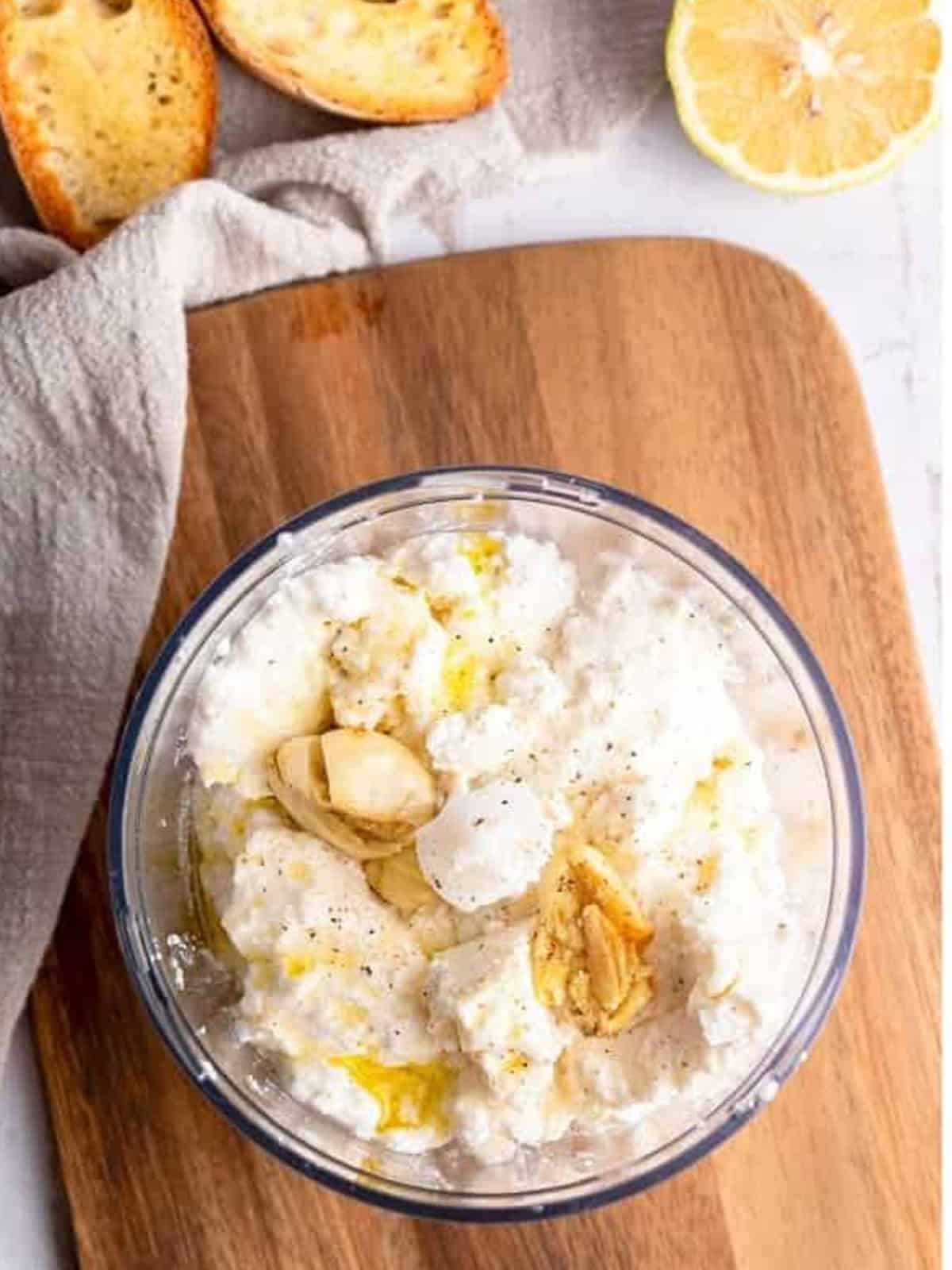 Ricotta cheese, garlic, and olive oil in a food processor for whipped ricotta dip.