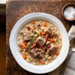 A rustic bowl of creamy White Bean and Pork Stew with tender pork, beans, carrots, and bacon.