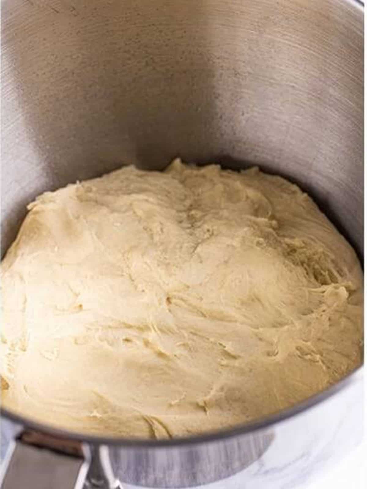Smooth, kneaded white bread dough in a stand mixer bowl.