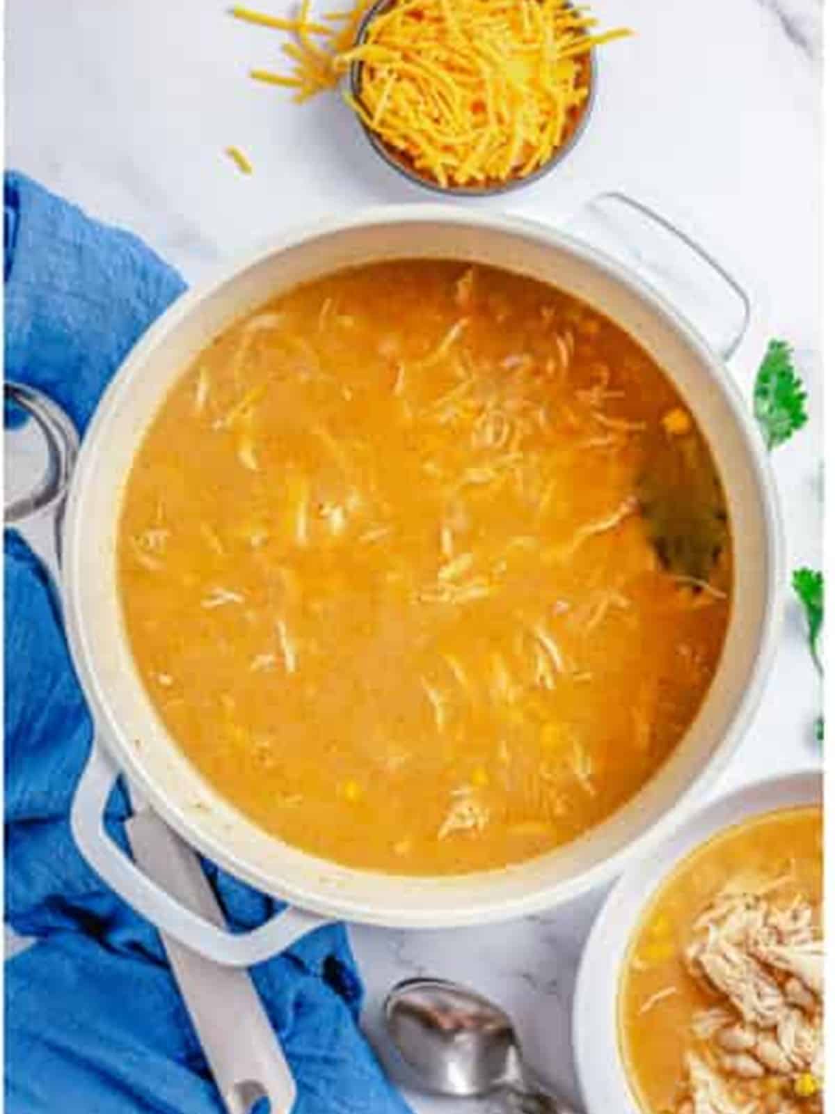 Finished pot of creamy white chicken chili topped with shredded cheese.