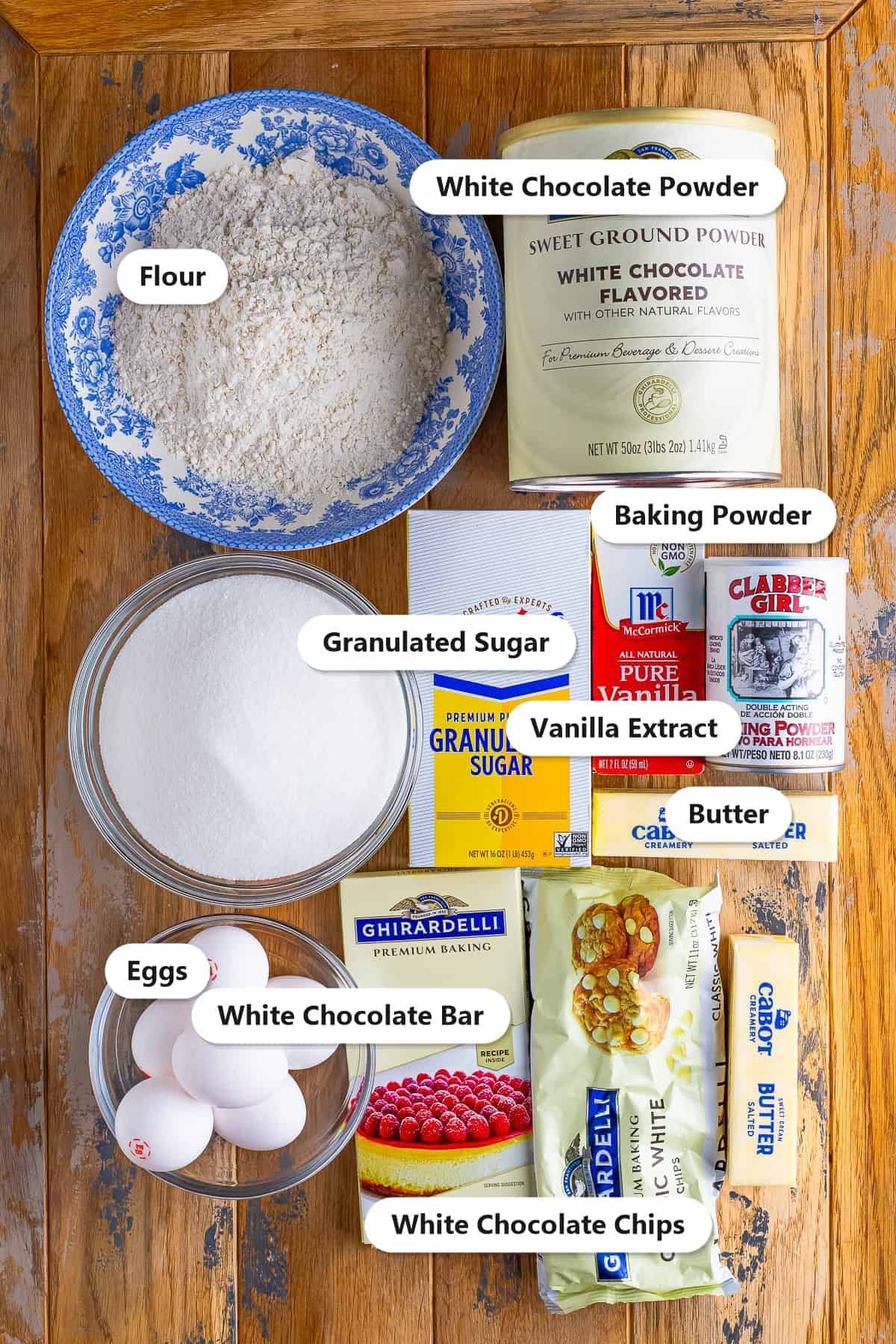 Labeled ingredients for white chocolate brownies including butter, white chocolate chips, flour, white chocolate powder, sugar, eggs, vanilla, and a white chocolate bar.