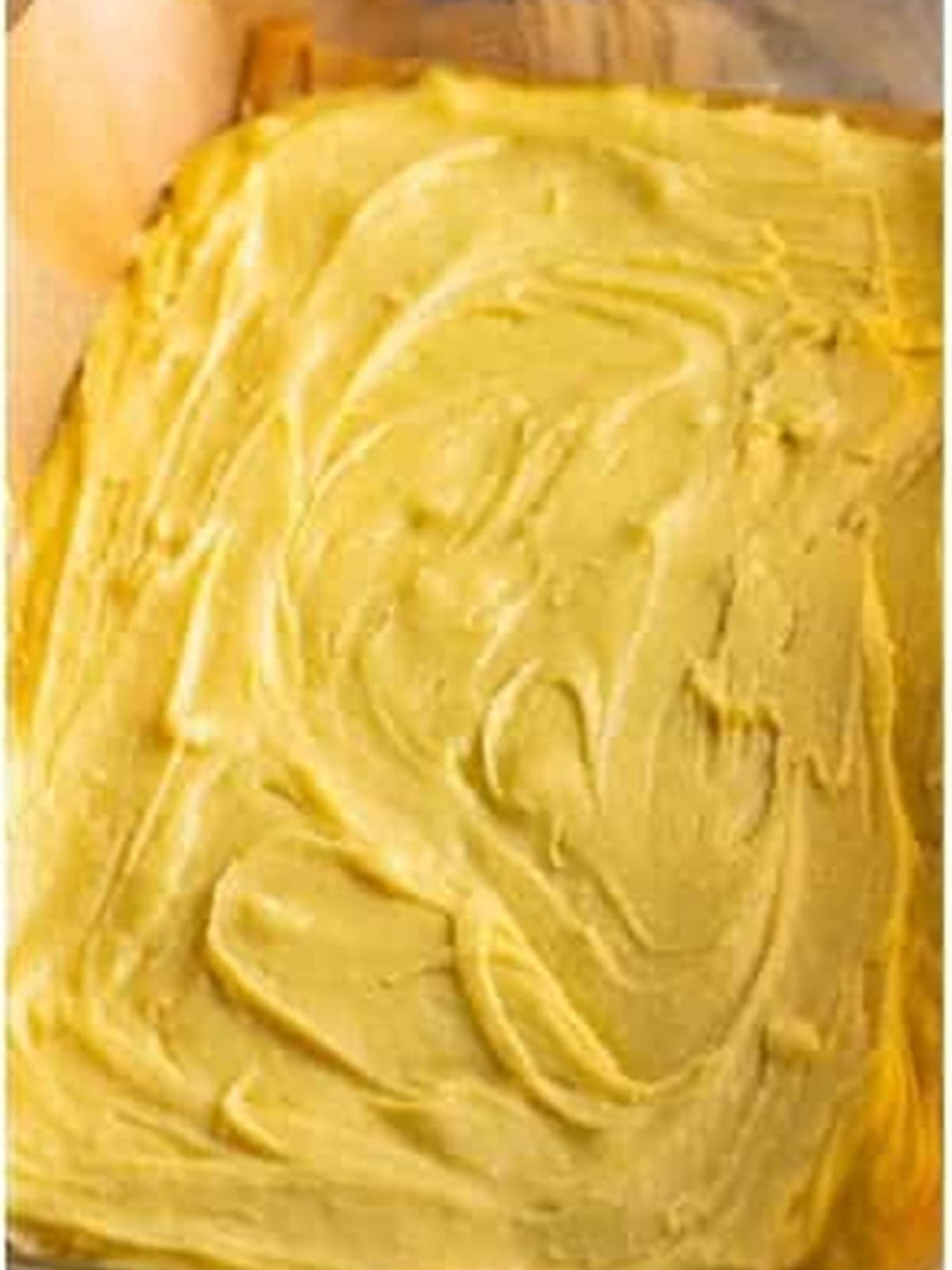 White chocolate brownie batter spread into a parchment lined baking dish.
