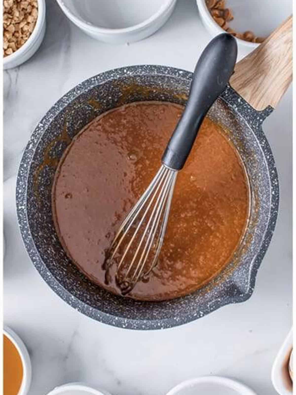Butterscotch mousse being whisked in a saucepan.