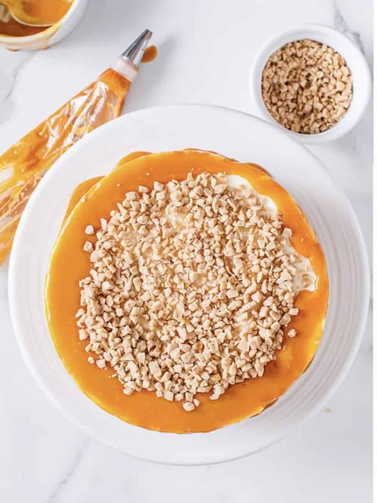 Butterscotch sauce drizzling from a spoon over the mousse cake.