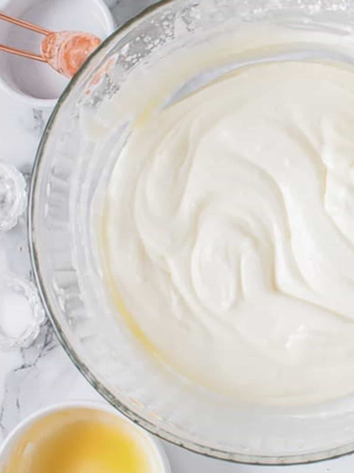 White chocolate mousse being whipped in a glass bowl.