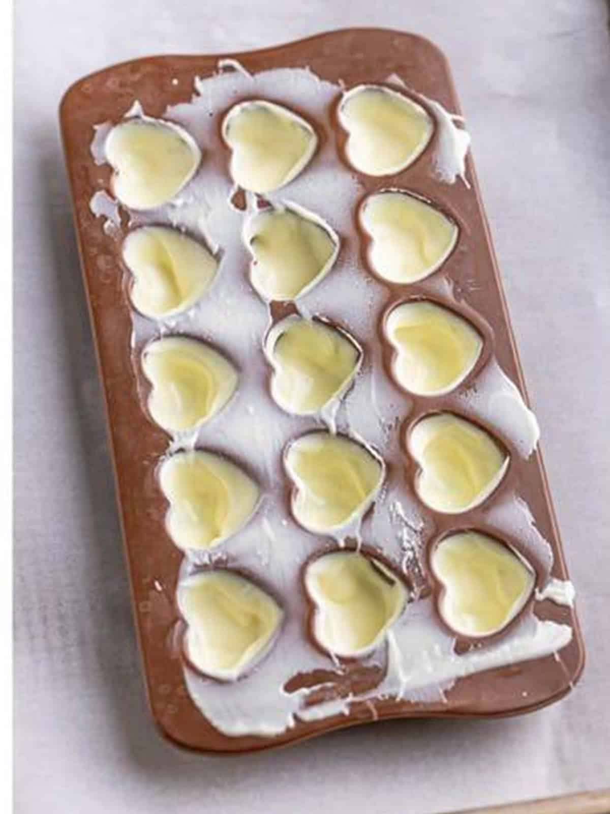 White chocolate coating silicone heart molds for white chocolate truffles.
