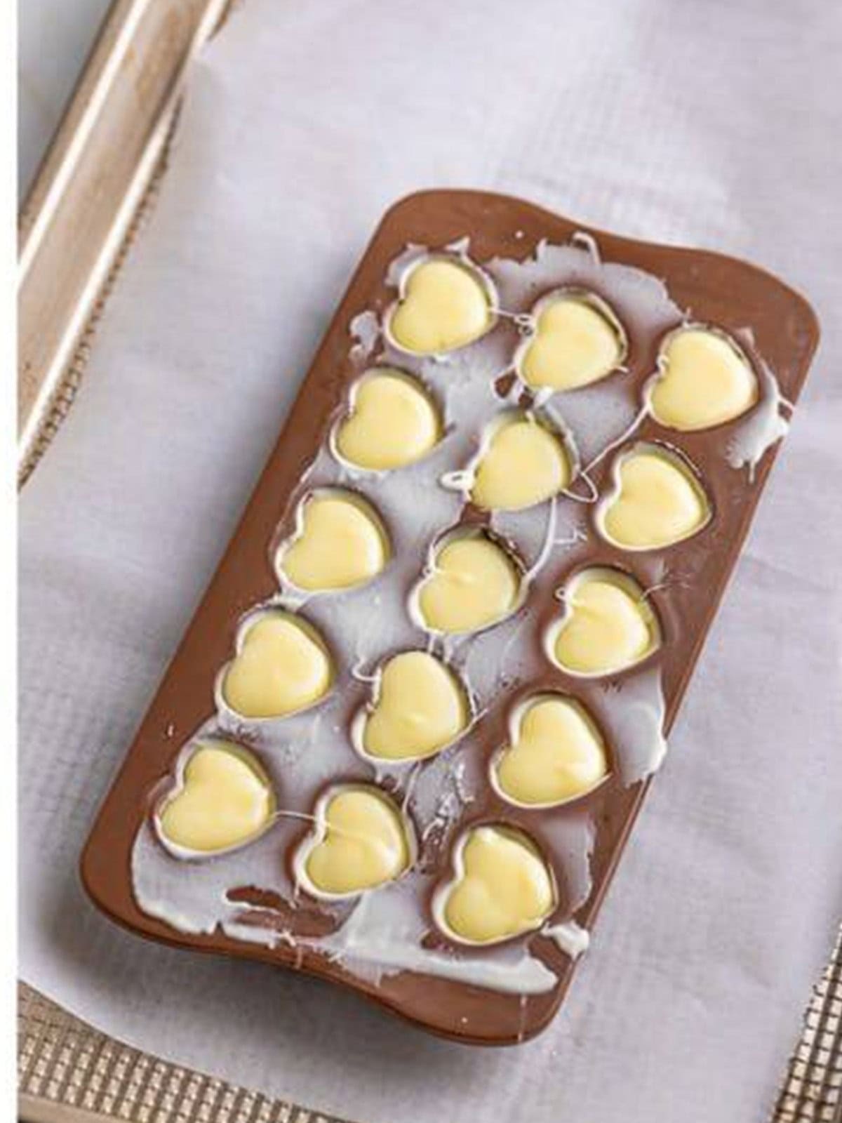 Piping white chocolate ganache into the heart molds for white chocolate truffles.