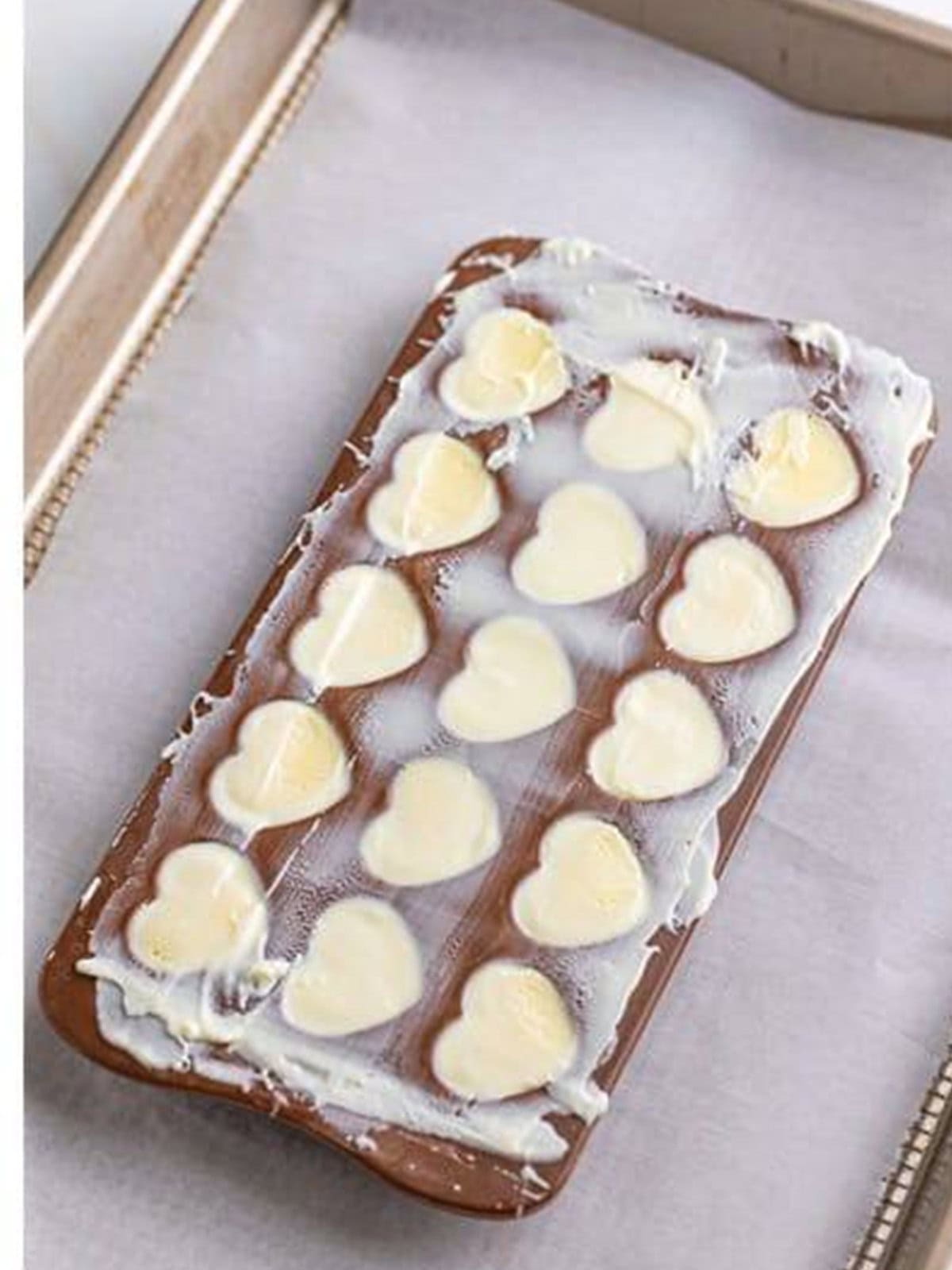 Sealing the filled white chocolate truffle molds with melted chocolate.