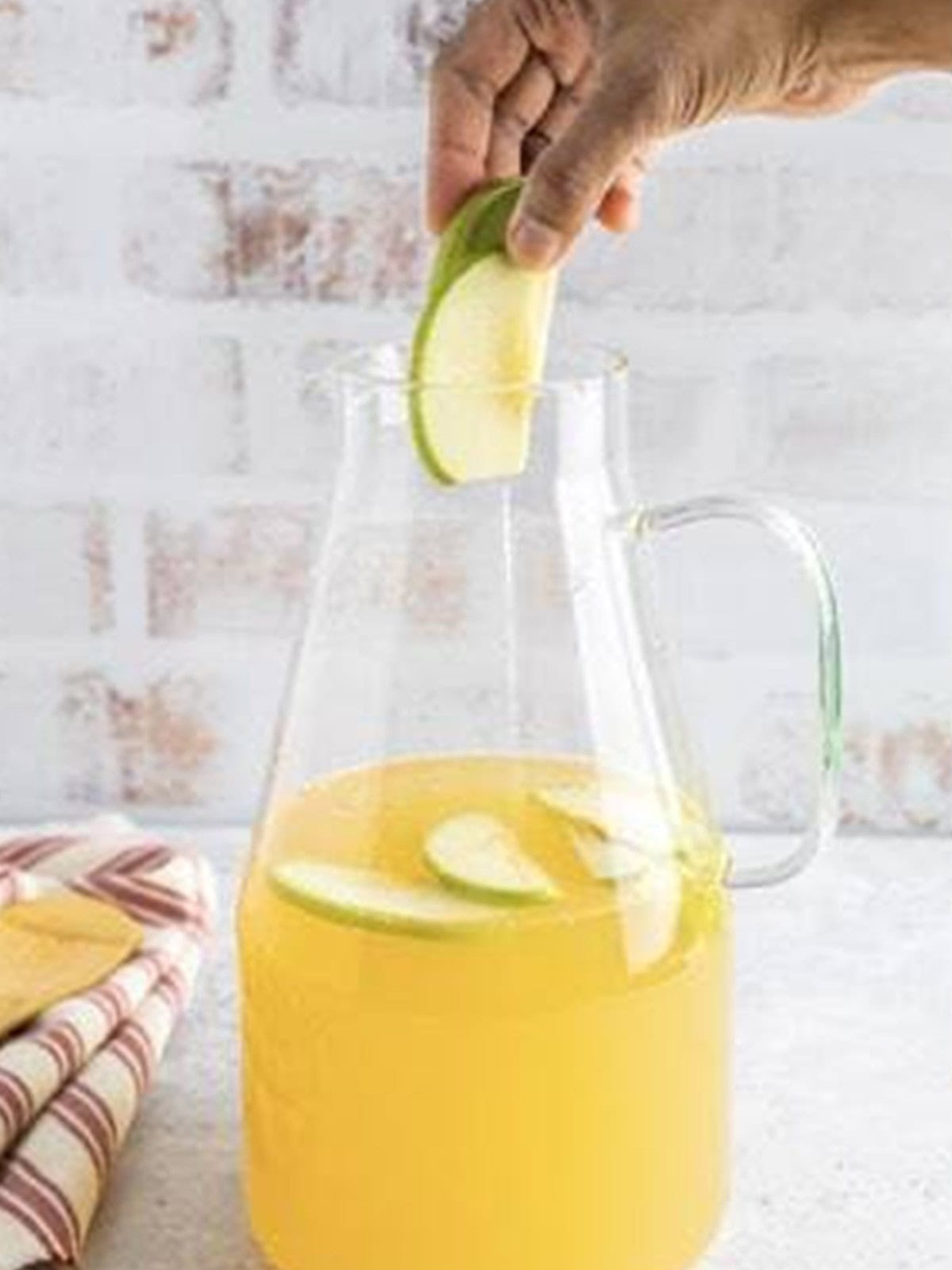 Adding sliced apples to the white wine sangria.