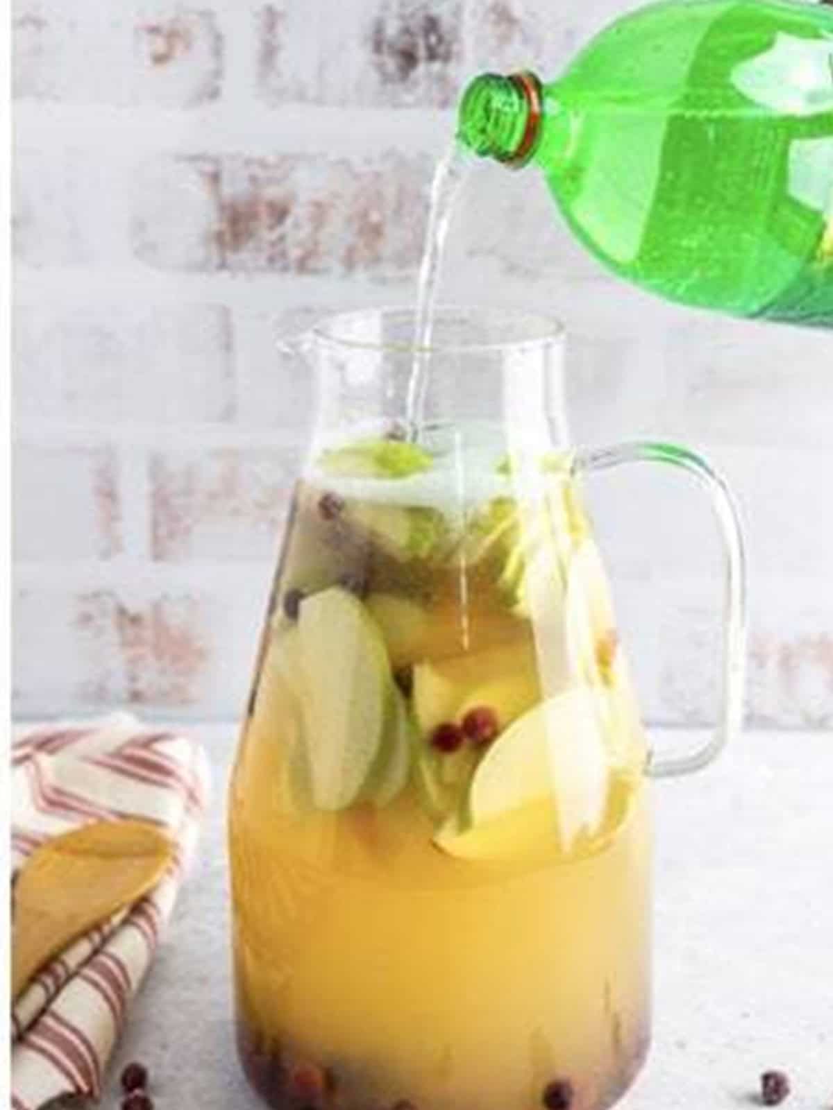 Topping the white wine sangria with soda.