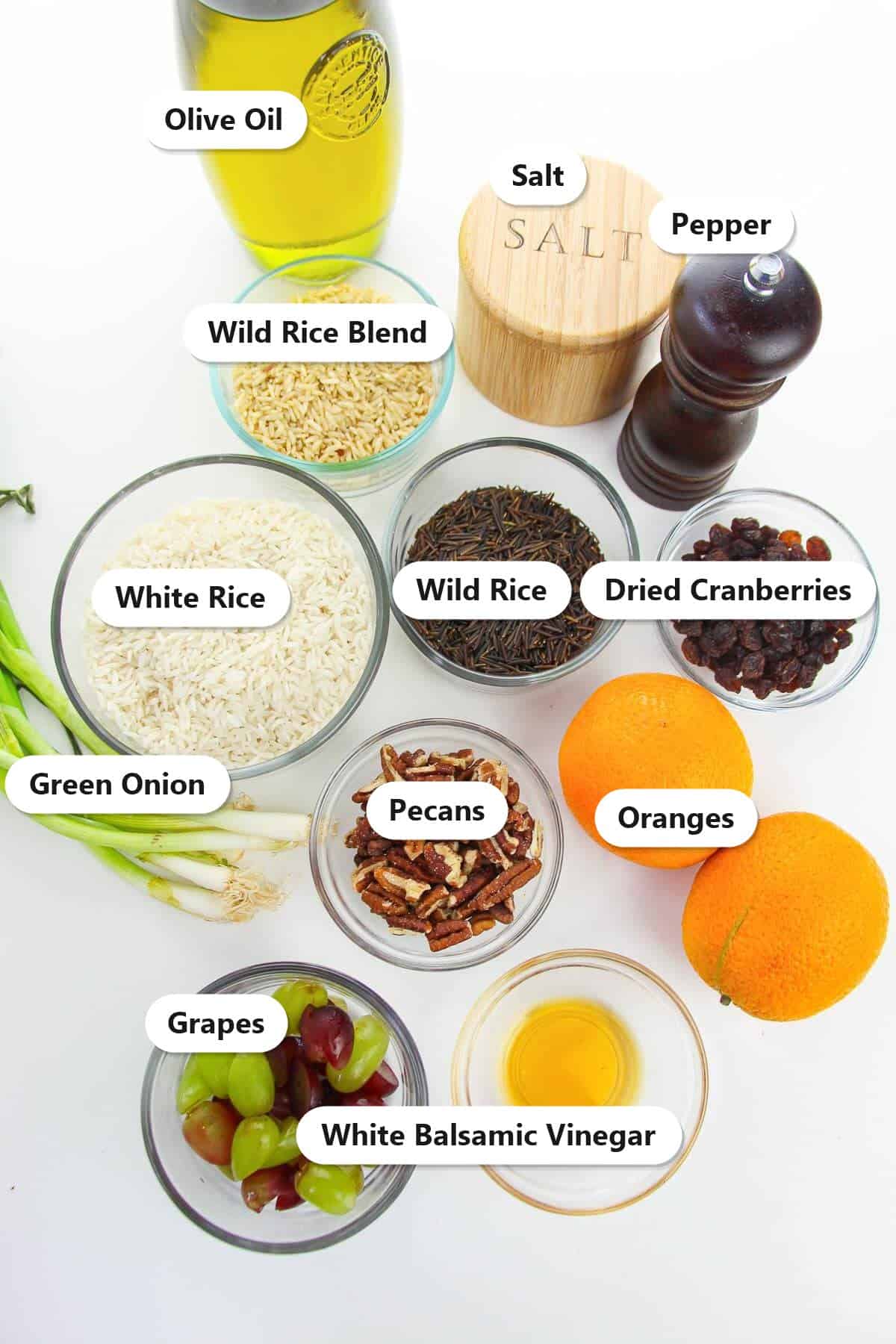 Labeled ingredients for wild rice salad including wild rice blend, oranges, grapes, pecans, dried cranberries, green onion, and white balsamic vinegar.