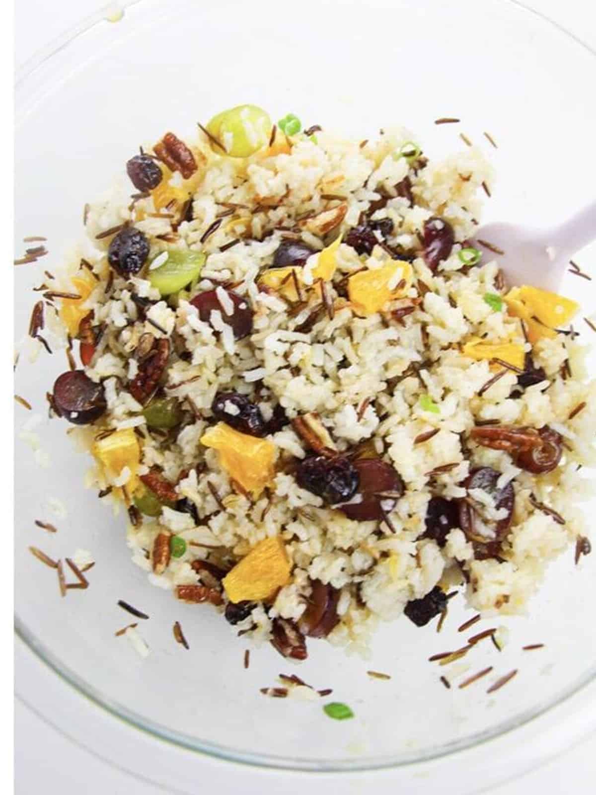 Tossed wild rice salad with orange, cranberries, and pecans ready to chill.
