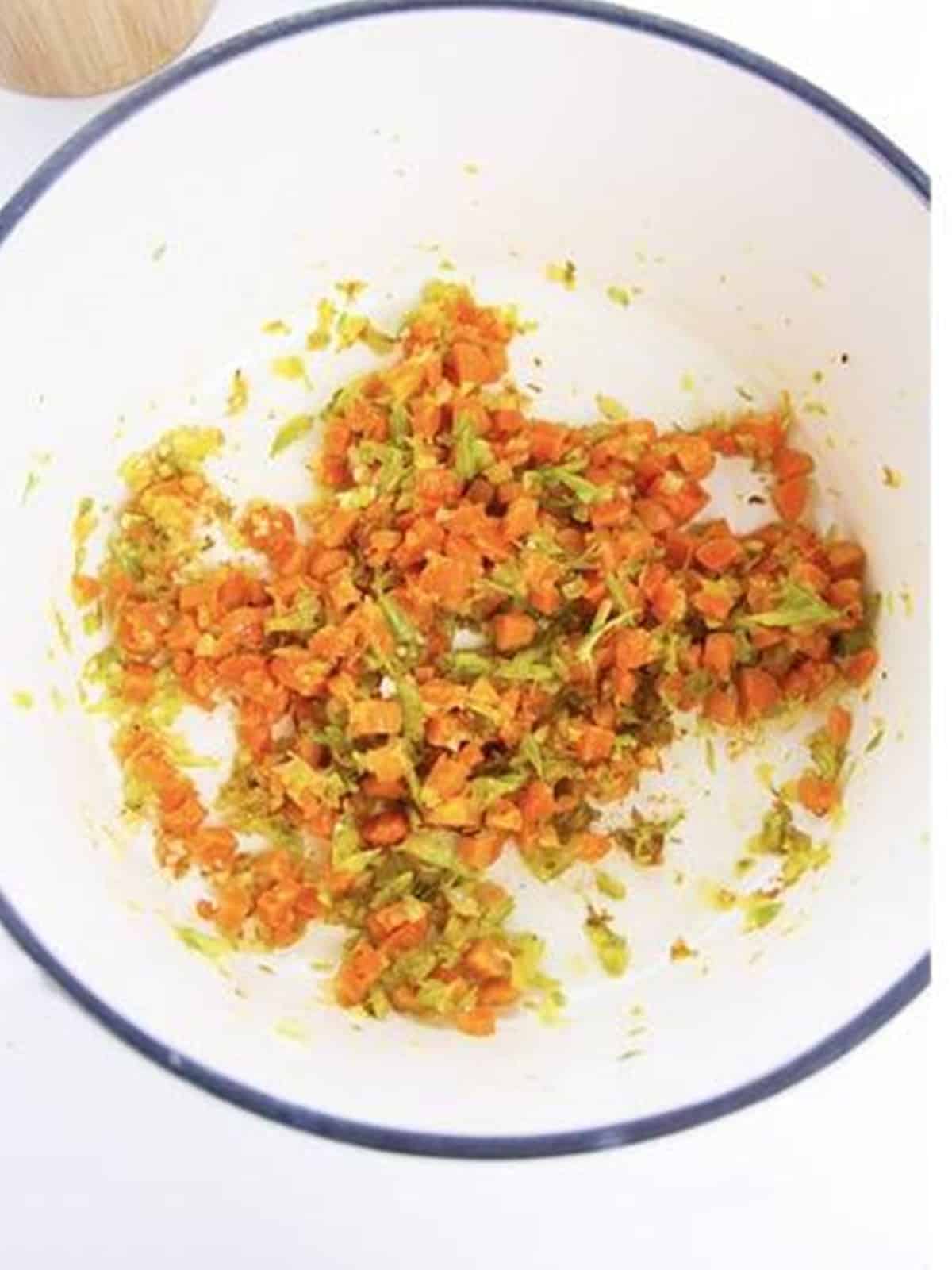 Diced onion, carrots, and celery sauteing in a pot with seasoning.
