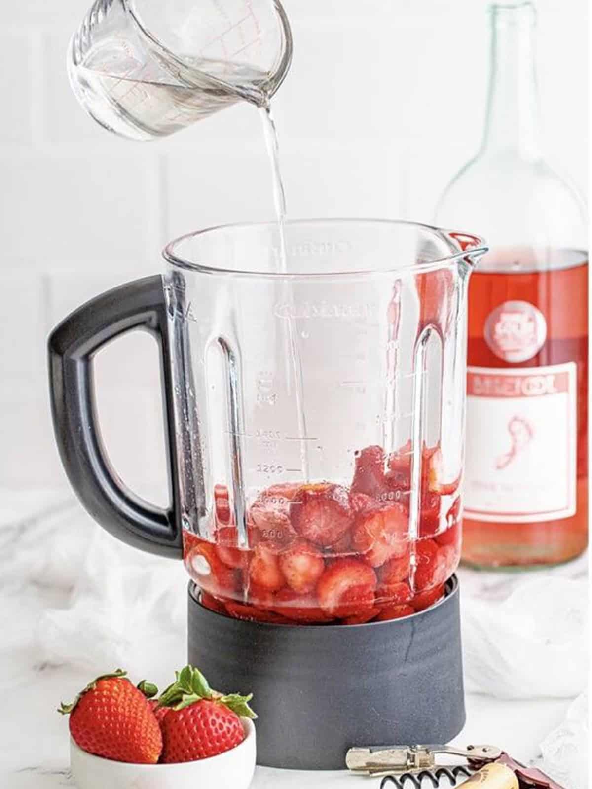 Blending the strawberries and wine into a smooth frozen slushie.