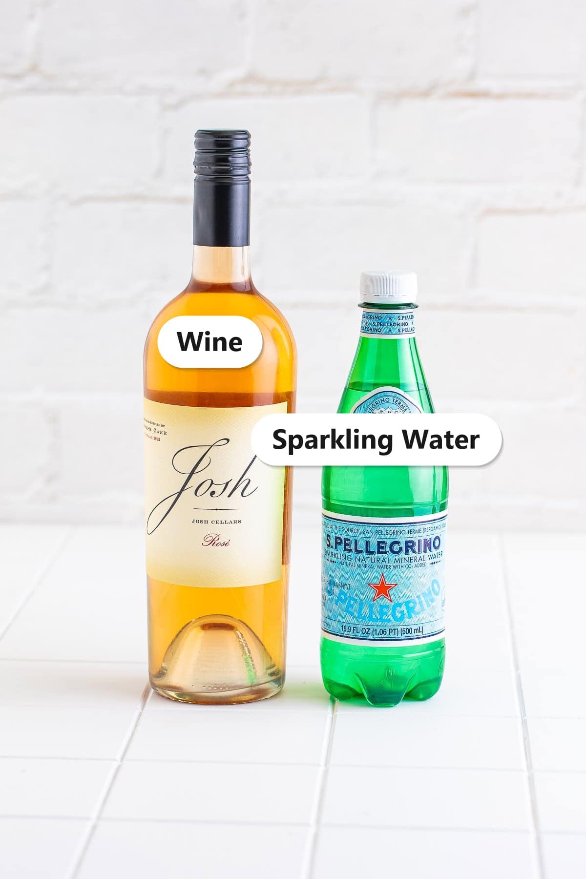 Labeled ingredients for a wine spritzer including a bottle of wine and sparkling water.