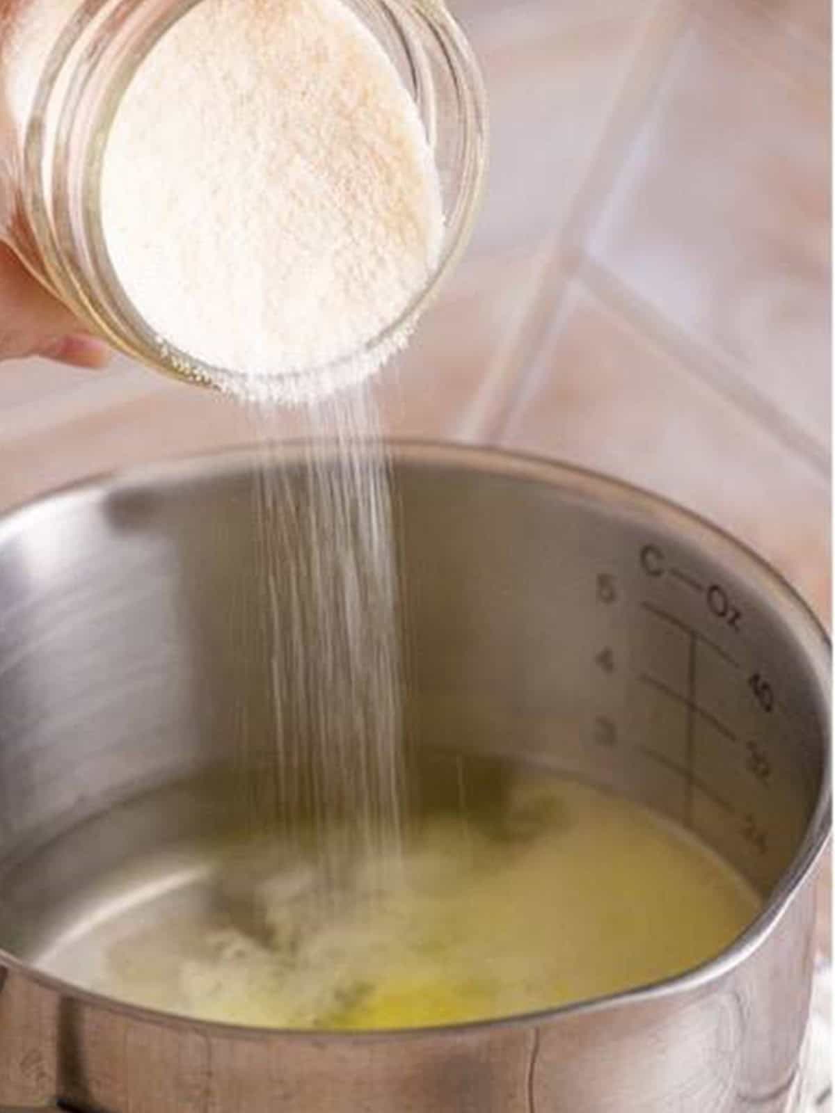 Pouring lemon jello powder into a saucepan of boiling water for woolworth cheesecake recipe.