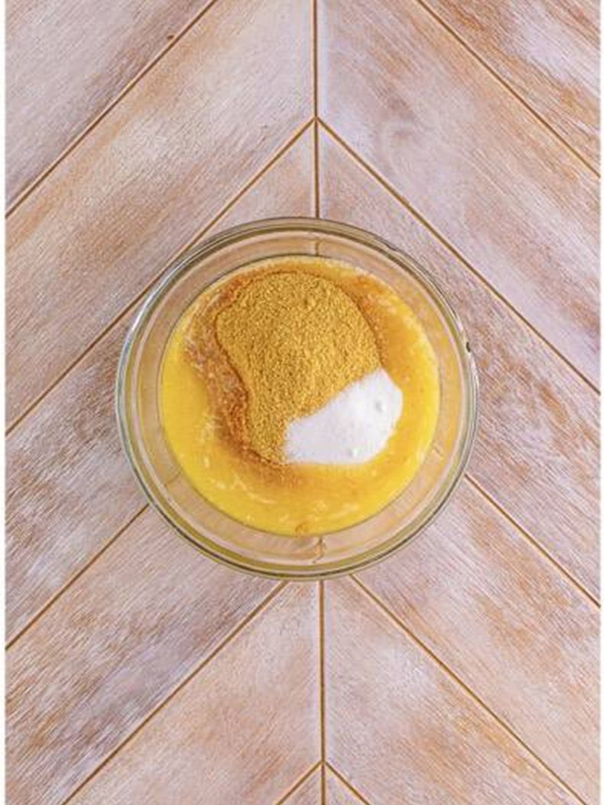 Graham cracker crumbs, melted butter, and sugar in a glass bowl for woolworth cheesecake crust.