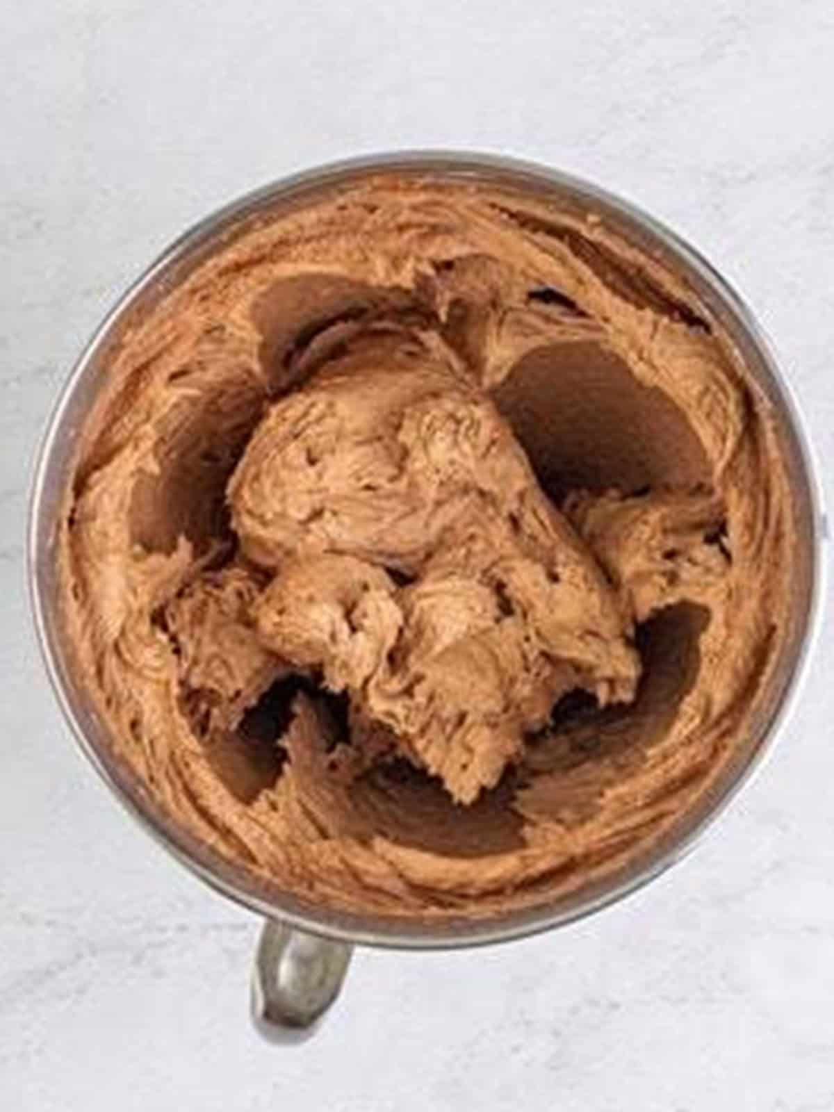 Whipped chocolate frosting for the Yellow Cake in a mixer bowl.