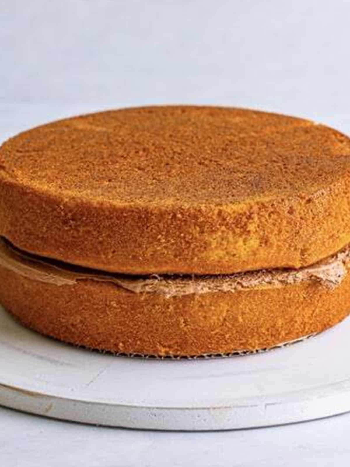 Stacking and filling the Yellow Cake layers with chocolate frosting.