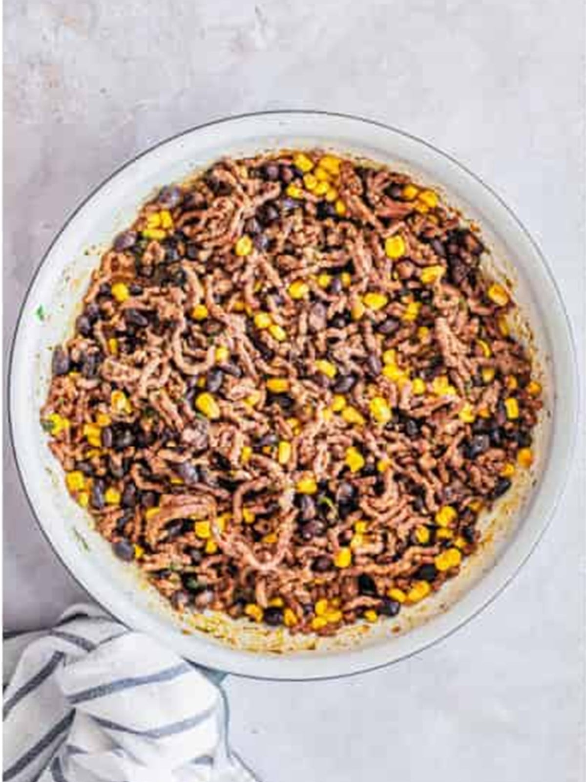Cooked ground beef, black beans, corn, and rice filling in a bowl for zucchini boats.
