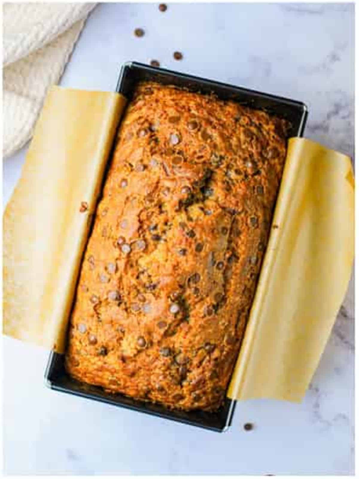 A golden baked loaf of chocolate chip zucchini bread in the pan.