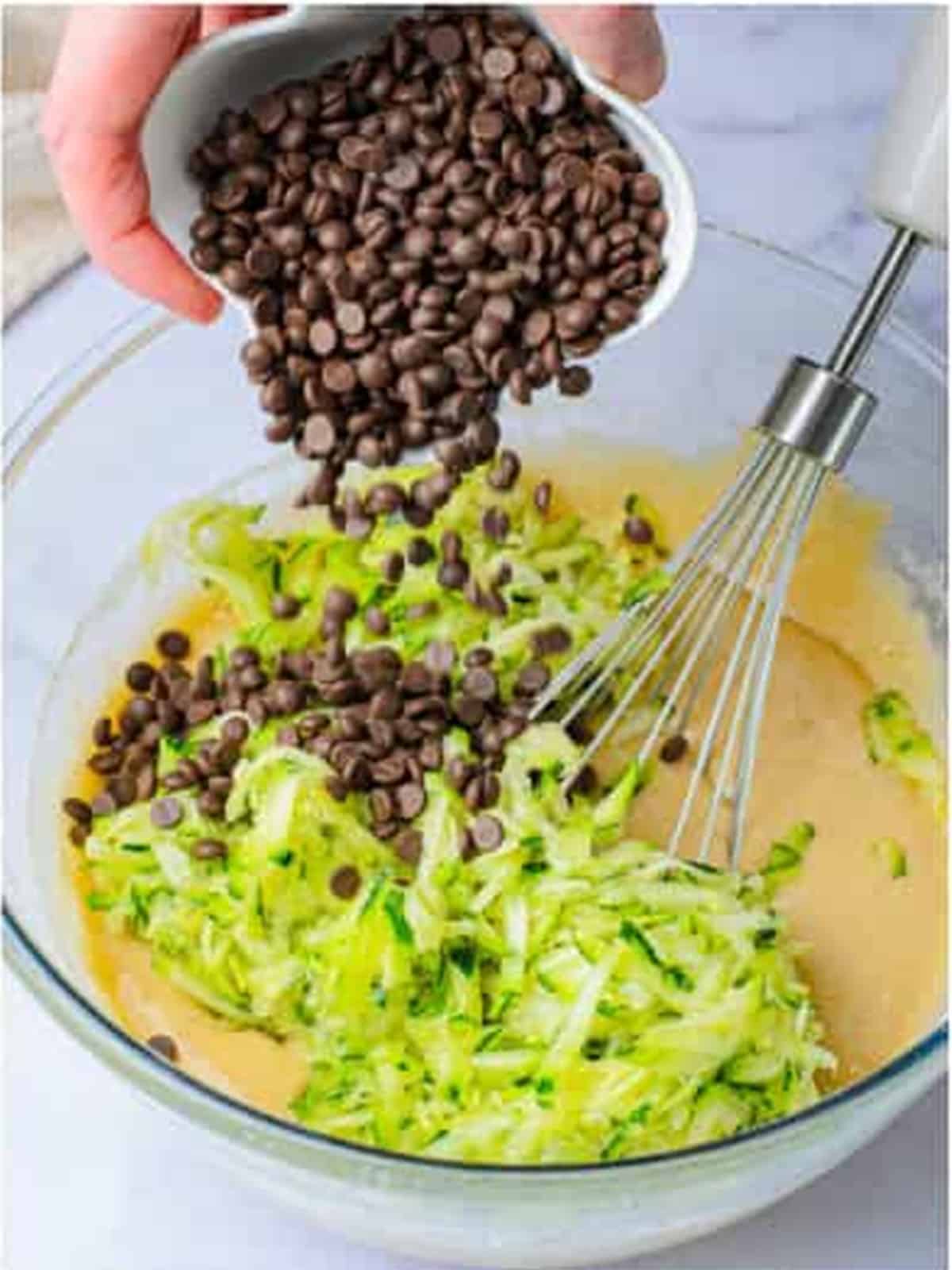 Grated zucchini and chocolate chips being folded into the batter.