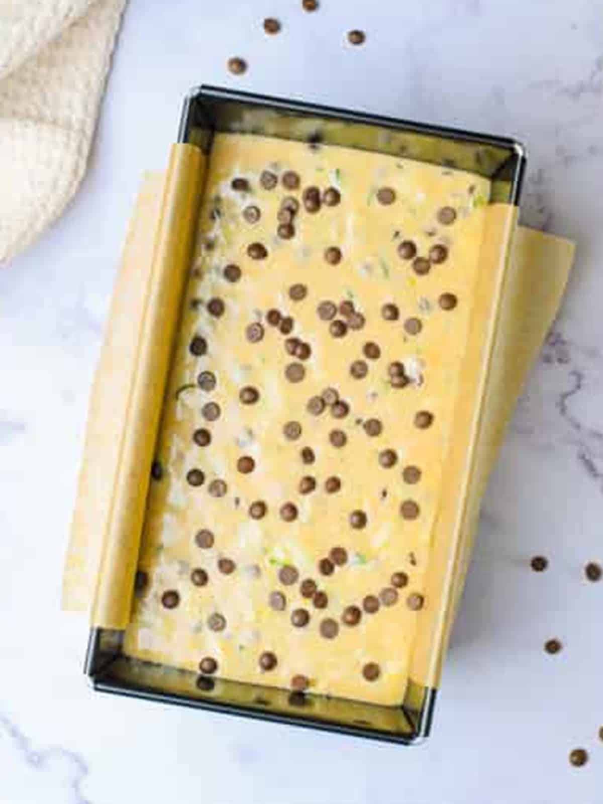 Chocolate chip zucchini bread batter poured into a parchment lined loaf pan.