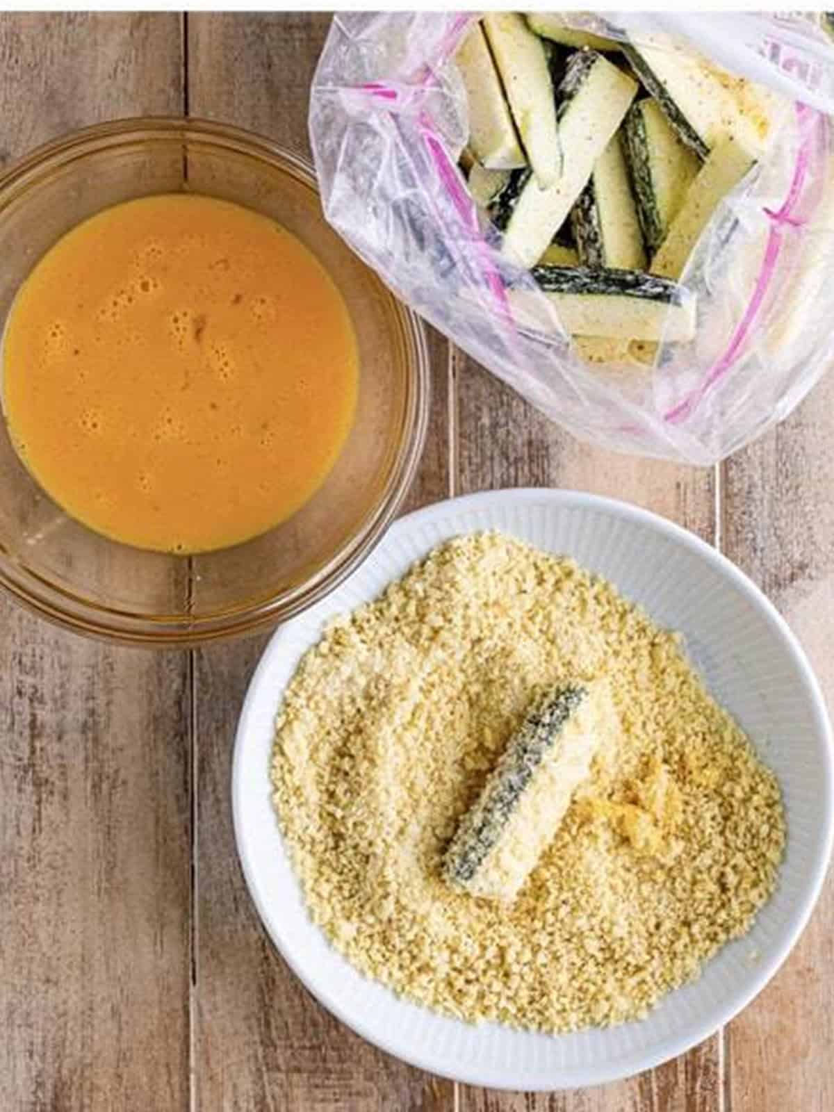A zucchini stick pressed into the panko and parmesan breadcrumb mixture.