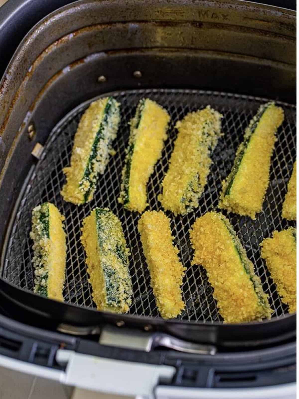 Breaded zucchini sticks arranged in a single layer in an air fryer basket.