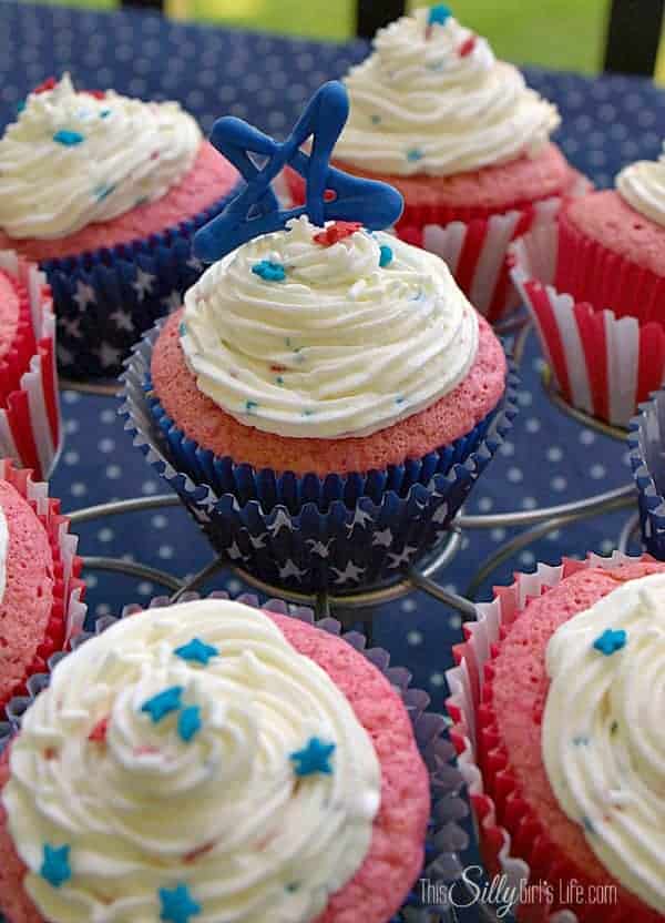Frosted 4th of July strawberry cupcakes with red and blue star sprinkles on a cupcake stand.