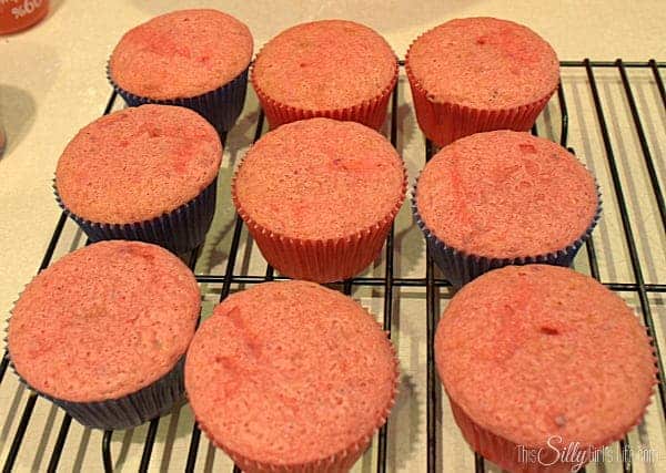 Baked strawberry cupcakes cooling on a wire rack.
