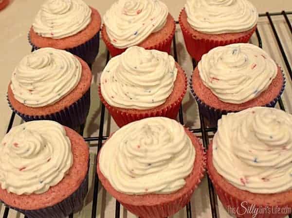 Strawberry cupcakes topped with swirls of funfetti buttercream on a cooling rack.
