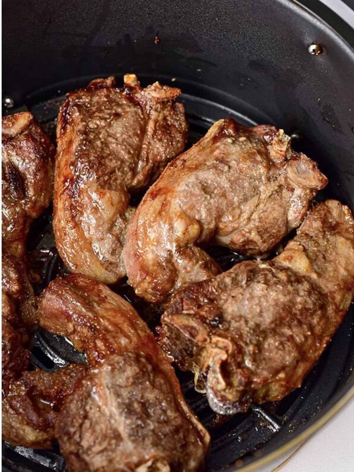 Browned air fryer lamb chops cooked in the basket.
