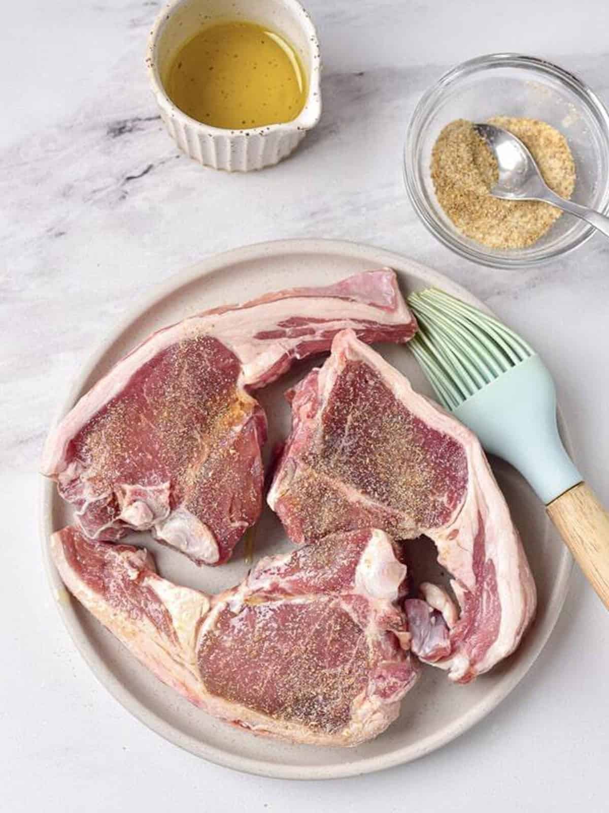 Lamb chops seasoned with garlic, salt, and coriander on a plate.