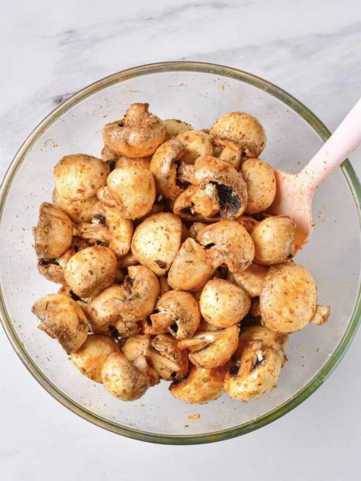 Mushrooms tossed with a spatula until evenly coated in oil and seasonings