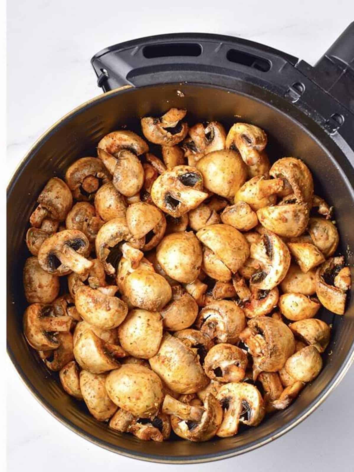 Seasoned mushrooms arranged in a single layer in the air fryer basket