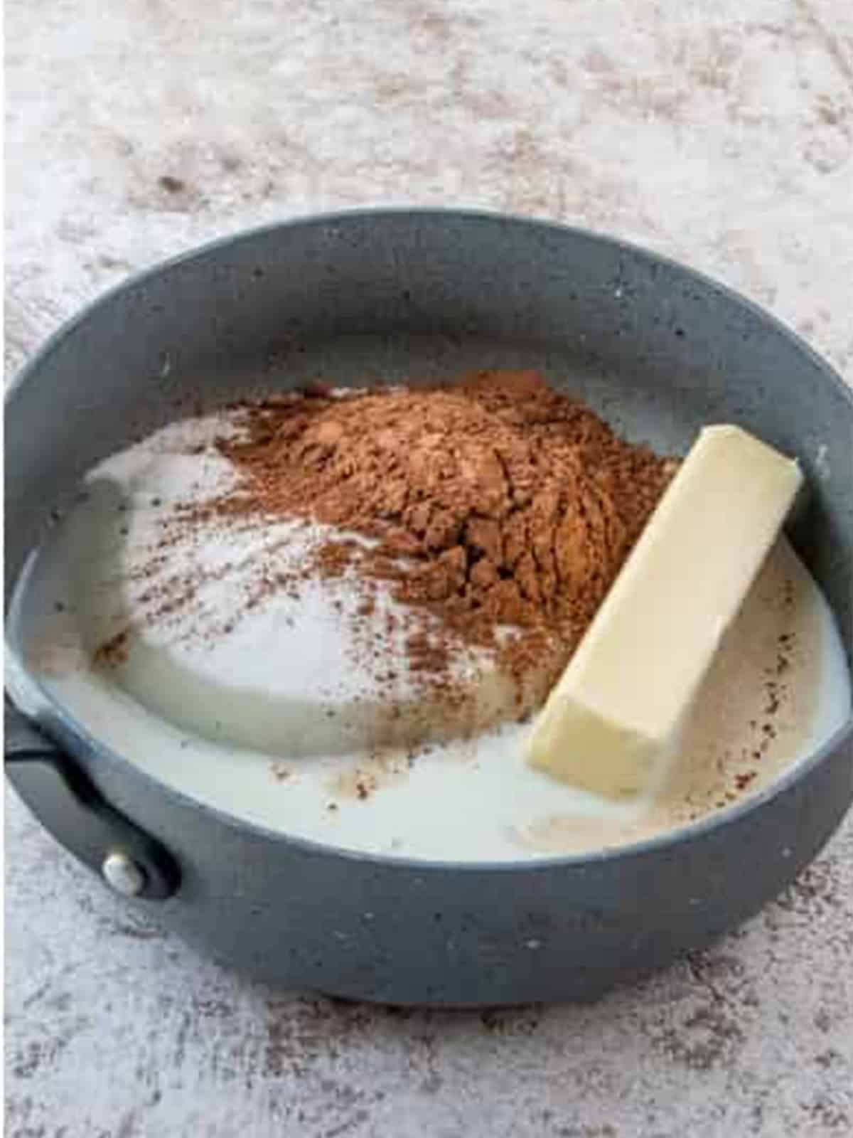 Butter, sugar, milk, and cocoa powder added to a saucepan for almond joy cookies