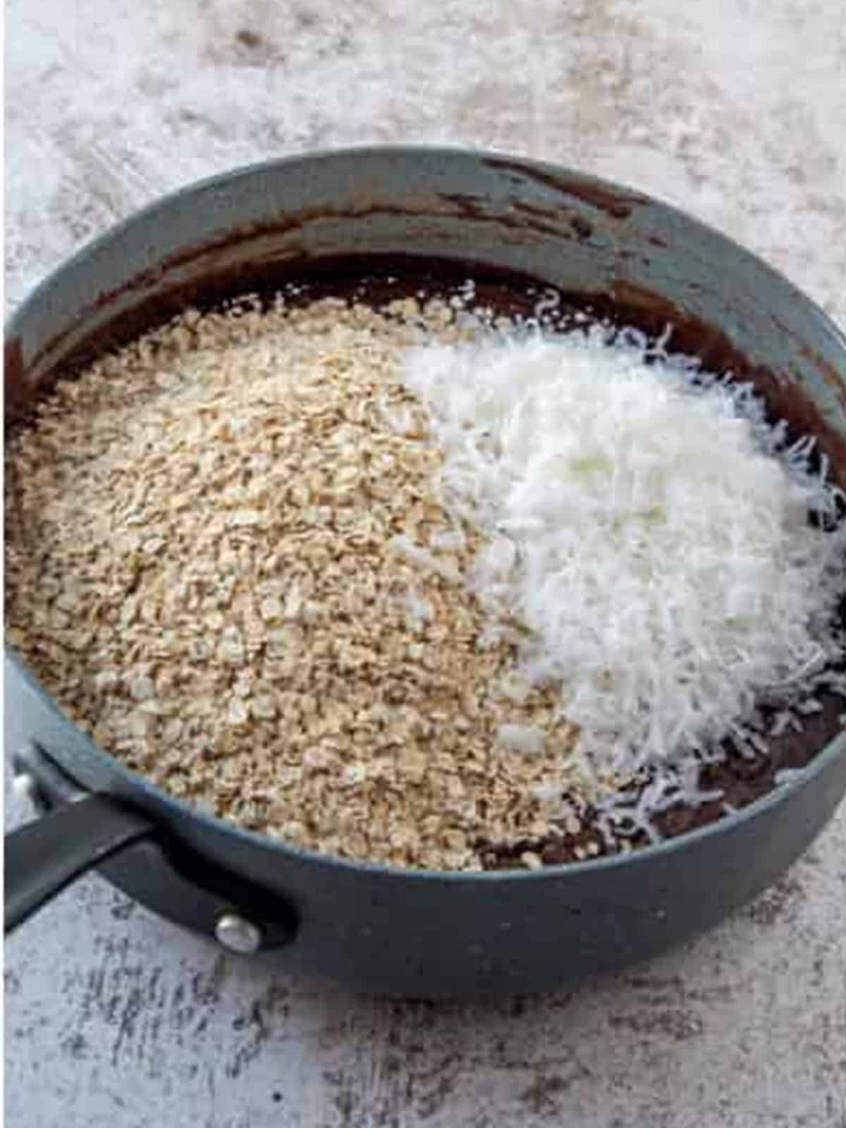 Quick oats and shredded coconut added to the chocolate mixture in the pan