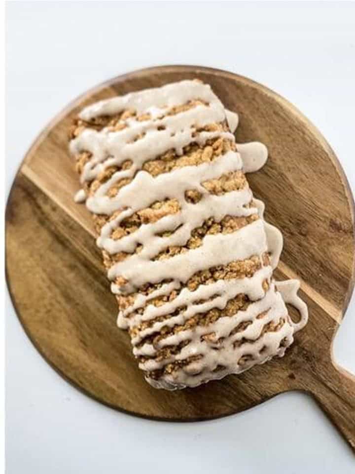 Pumpkin spice glaze drizzled over the baked Apple Bread loaf on a wooden board.