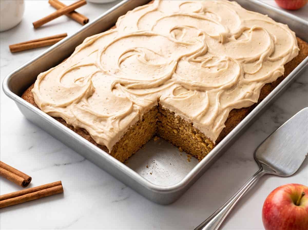 Apple Cider Cake frosted with brown sugar frosting in a pan with one slice removed.