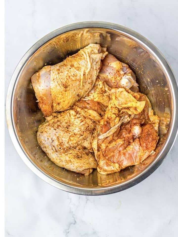 Seasoned chicken thighs stirred until coated on both sides ready to sear.